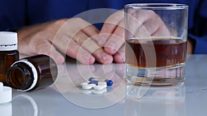 Alcoholic Person in front of Alcohol and Medical Pills with Hands Shaking