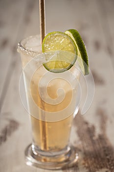 Alcoholic salty dog cocktail with grapefruit and lime in glass on wooden background, selective focus, vertical