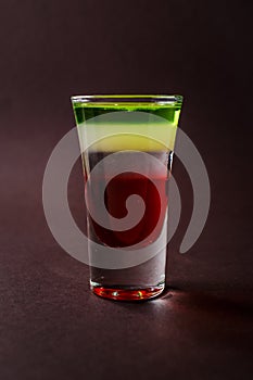 Alcoholic shot glass with grenadine, absent on elegant dark brow