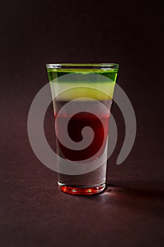 Alcoholic shot glass with grenadine, absent on elegant dark brow