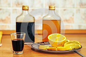 Alcoholic tincture in a glass glass puerh tea and slices of lemon on a plate.