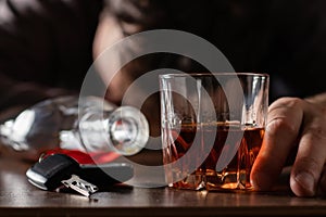 Alcoholism, alcohol addiction and people concept - male alcoholic with glass of whiskey lying or sleeping on table. Keys from auto