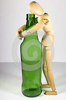 Alcoholism, alcohol addiction, social problem: a wooden dummy, a lonely drunkard, an alcoholic, hugging a bottle of beer photo