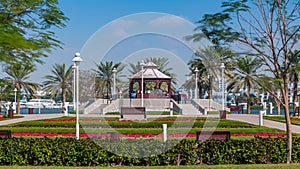 Alcove with green lawn, flowers and trees at Dubai Creek park timelapse. Dubai, United Arab Emirates