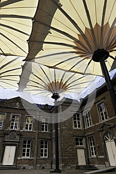 Alden Biesen castle with moat and modern huge umbrellas in Bilzen, Belgium