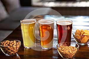 Ale, lager and beer in glasses. Pistachios, nuts and chips in glass plates on table