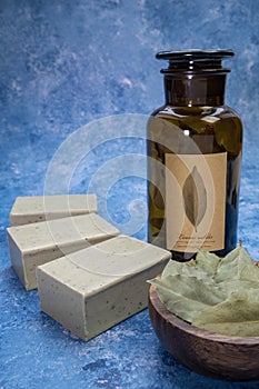 Aleppo soap and dray Laurus nobilis Leafs in a wooden plate and dark botanic glass bottle