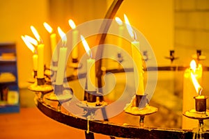 ALESUND, NORWAY - APRIL 04, 2018: Close up of many candles over a metallic chandelier inside of the Bodo cathedral in