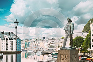 Alesund, Norway. Statue Of Young Sailor-fisher Boy On Brosundet Canal. Old Wooden Houses In Summer Day