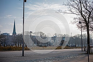 Alexanderplatz square in Berlin on a sunny spring day. Looking ferom the side towards center, hazy backlit atmosphere. People on