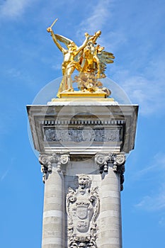 Alexandre III bridge golden statue with winged horse and column in a sunny day, blue sky in Paris