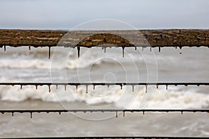 Algae growing on pier railing, with stormy sea waves foam and water drops in the background