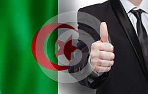 Algerian concept. Businessman showing thumb up on the background of flag of Algeria