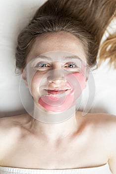 Alginic mask on the face of young woman in beauty salon. cosmetic procedure to make skin younger and fresher on white background