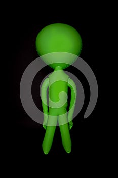 Alien. Blank inflatable little green man. Stereotypical body shape isolated against black background.