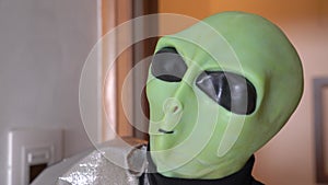 Alien nods head approvingly and enters the room, close up. Man in alien costume came to fancy dress party. Actor plays