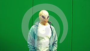 Alien ufo mask with casual clothes against green wall background dance and move funny - Crazy fun extraterrestrial living like