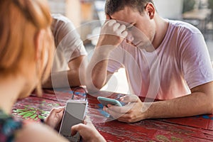 Alienation addiction. Friends sitting in cafe, typing on their phones photo