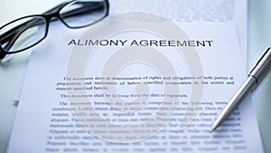 Alimony agreement lying on table, pen and eyeglasses on official document