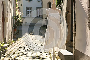 aline summer dress on mannequin, cobblestone street setting photo