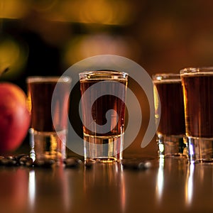 Alkohol shots coffee beans and apple on bar table on blurred background