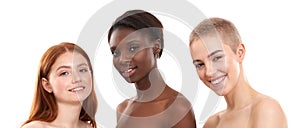 We are all beautiful. Three positive multicultural young women looking at camera and smiling while posing in studio over