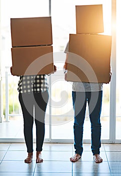 All boxed up and ready to go. an unidentifiable young couple carrying boxes on moving day.