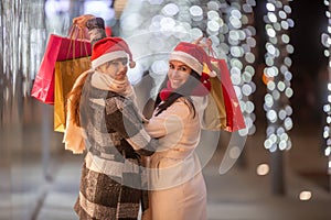 With all Christmas presents bought in shopping bags, two happy women finish their purchases for the festive period