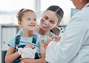 All done. a doctor putting a plaster on a little girls arm while administering an injection in a clinic.