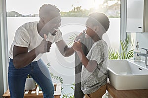 All freshened up and ready for an awesome day. Shot of a father showing thumbs up to his son while drying his face with