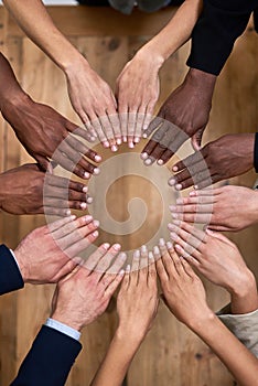 All hands on deck. High angle shot of a group of unidentifiable businesspeople making a circle with their hands in the