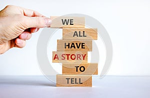 We all have a story to tell symbol. Wooden blocks with words `We all have a story to tell`. Businessman hand. Beautiful white