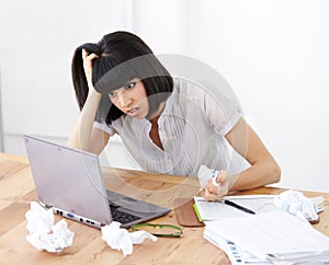 All her work has amounted to nothing. A shocked businesswoman looking at her laptop screen amidst crumpled documents.