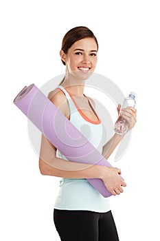 This is all I need for my yoga class. Portrait of a beautiful young woman holding her exercise mat and a bottle of water