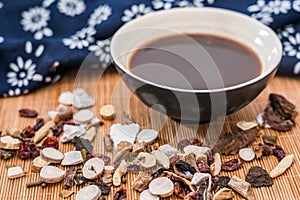 All kinds of traditional Chinese medicine and a bowl of traditional Chinese medicine soup scattered on the bamboo mat