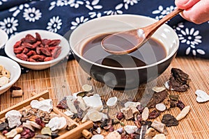 All kinds of traditional Chinese medicine and a bowl of traditional Chinese medicine soup scattered on the bamboo mat