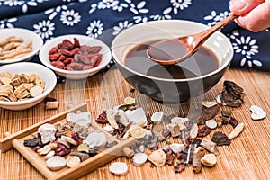 All kinds of traditional Chinese medicine and a bowl of traditional Chinese medicine soup scattered on the bamboo mat