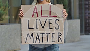 ALL LIVES MATTER on a cardboard poster in the hands of female protester activist. Closeup of poster and hand. Rallies