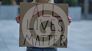 ALL LIVES MATTER on cardboard poster in hands of female protester activist. Stop Racism concept, No Racism. Rallies