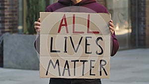 ALL LIVES MATTER on cardboard poster in hands of male protester activist. Stop Racism concept, No Racism. Rallies