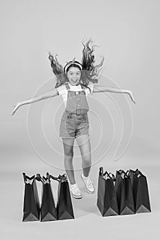 All for me. Little girl with shopping packages. Happy child with bags. Small child in summer style. Seasonal sales
