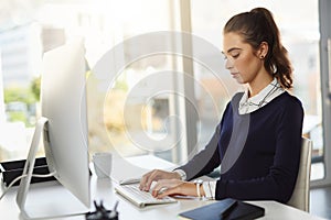 All my hard work will pay off one day. an attractive young businesswoman sitting at her desk and using her computer in a