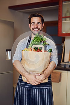 All my meals start with exceptional ingredients. Portrait of a happy young man posing with a bag of groceries in his