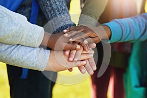 All for one and one for all. Shot of a group of unrecognizable elementary school kids joining their hands together in a