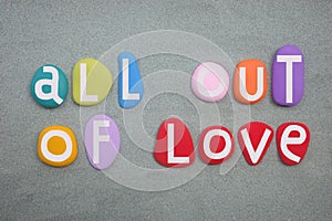 All out of love, creative slogan composed with multi colored stone letters over green san