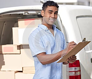 All parcels are safe and sound. Portrait of a young delivery man writing on a clipboard while loading boxes from a van.