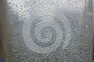 Small, round, spherical bubbles covered the surface of a plastic container of water. Mysterious and unusual light background.