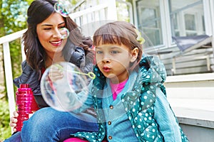 All that practice is paying off. a mother watching her daughter blow bubbles outside.