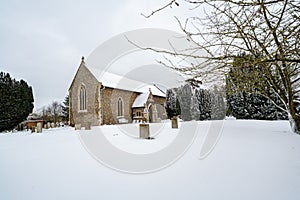 All Saints church in the small village of Sutton in the British countryside, it is totally covered in deep snow during a rare snow