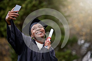 All smiles on her big day. a young woman taking selfies on graduation day.